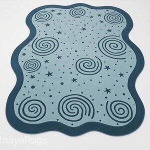 Könnte beinhalten: Hellblauer Teppich mit dunkelblauem Rand und unregelmäßiger Form. Der Teppich hat ein Muster aus dunkelblauen Spiralen, Sternen und Punkten. Der Teppich ist für die Inneneinrichtung konzipiert.
