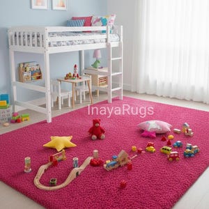 May include: A bright pink shag rug fills a child's bedroom, with a white bunk bed, small table, and toys scattered across it. A wooden train track, toy cars, and a teddy bear are visible.