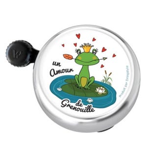 Può includere: Un campanello per bicicletta argentato con una leva nera. La faccia del campanello presenta un ranocchio dei cartoni animati con una corona, seduto su una ninfea, con le parole "un Amour de Grenouille" e cuori rossi. La rana ha una freccia in bocca.