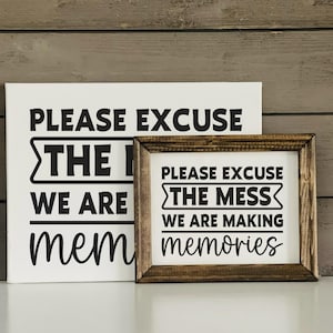 May include: Two white wooden signs with black text. The top sign says "Please excuse the mess we are making memories". The bottom sign says "Please excuse the mess we are making memories".