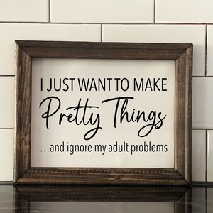 May include: A framed sign with the text "I just want to make pretty things... and ignore my adult problems". The sign is on a white tiled surface.