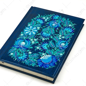 May include: A blue leather journal with a hand-painted floral design in shades of blue and green. The flowers are stylized and have a whimsical feel.