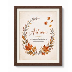 Könnte beinhalten: Ein gerahmter Wandkunstdruck mit einem Kranz aus herbstlichen Aquarellblättern in Orange-, Rot- und Brauntönen. Der Text lautet: Autumn reminds us that letting go can be beautiful. Der Druck befindet sich in einem dunkelbraunen Holzrahmen.