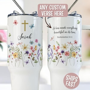 May include: Two white stainless steel tumblers with handles and clear lids, featuring a colorful wildflower print, a gold cross, the name Sarah, and the text He has made everything beautiful in its time. Ecclesiastes 3:11 with a custom verse option.