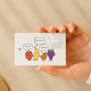 Puede incluir: Una tarjeta blanca con una ilustración de dibujos animados de frutas, incluyendo una fresa, un plátano, una naranja y uvas, cada una con bocadillos. Los bocadillos dicen "sweet", "summer", "ahead" y "friend!"