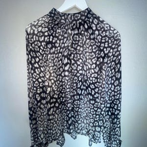 May include: A black and white leopard print blouse with long sleeves and a high neck.