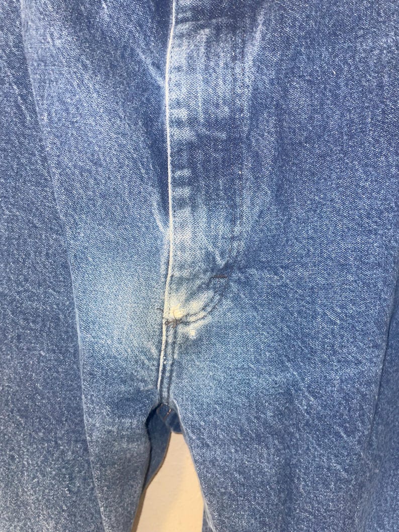 May include: Close-up of blue denim fabric with a visible seam down the centre.