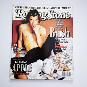Puede incluir: Portada de la revista Rolling Stone con Gavin Rossdale de Bush. La portada incluye texto sobre la banda, P.J. O'Rourke y la caída de Apple. La revista tiene un encabezado rojo y blanco.