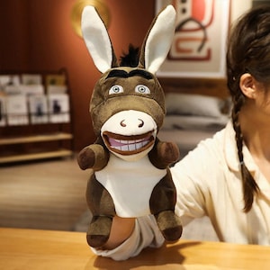 May include: A brown and white donkey puppet with a big toothy grin. The puppet has large ears and a black mane.