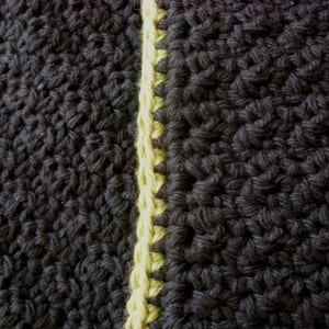 May include: Close-up of black and yellow crocheted fabric. The fabric is made with a single crochet stitch and has a textured look.