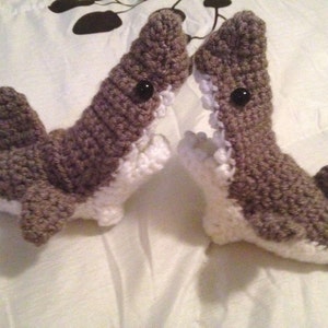 May include: Two crocheted gray and white shark toys with black eyes. The sharks have open mouths and are made with a soft yarn.