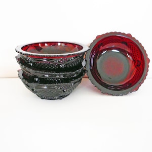 May include: Set of four ruby red glass bowls with a decorative pattern. The bowls are stacked on top of each other.