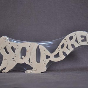 May include: A wooden squirrel puzzle with the word "SQUIRREL" cut out of the body. The puzzle is packaged in a clear plastic bag.