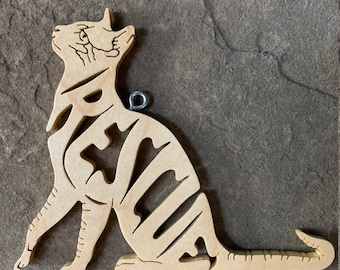 May include: A wooden cat ornament with a puzzle piece design. The ornament is light brown and has a metal loop for hanging.