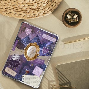 May include: A clear tablet case with a collage design featuring purple mountains, stars, and text. Decorative elements include a gold frame, heart-shaped stickers, and the words "Bat Boys" and "Cauldron Boil Me".
