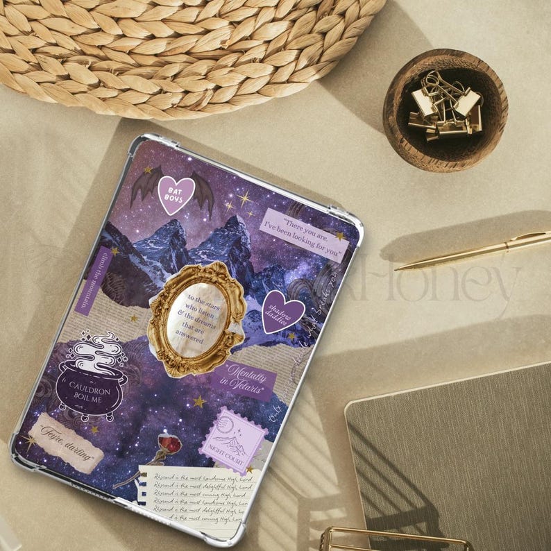 May include: A clear tablet case with a collage design featuring purple mountains, stars, and text. Decorative elements include a gold frame, heart-shaped stickers, and the words "Bat Boys" and "Cauldron Boil Me".