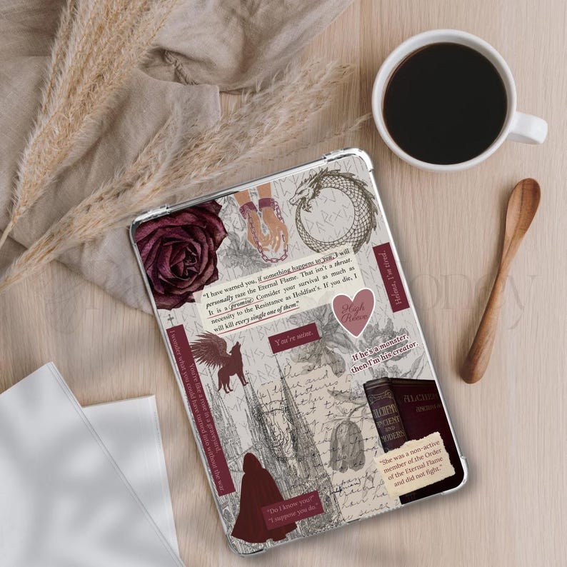 May include: A clear tablet case with a collage design featuring a burgundy rose, a dragon, and text excerpts. The case has a variety of stickers with quotes and illustrations. A cup of coffee and a wooden spoon are on the table.
