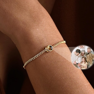 May include: A gold chain bracelet with a circular charm, worn on a person's wrist. A small, circular image shows a family portrait. The text "LeslieArtJewelCo" is in the bottom right corner of the image.