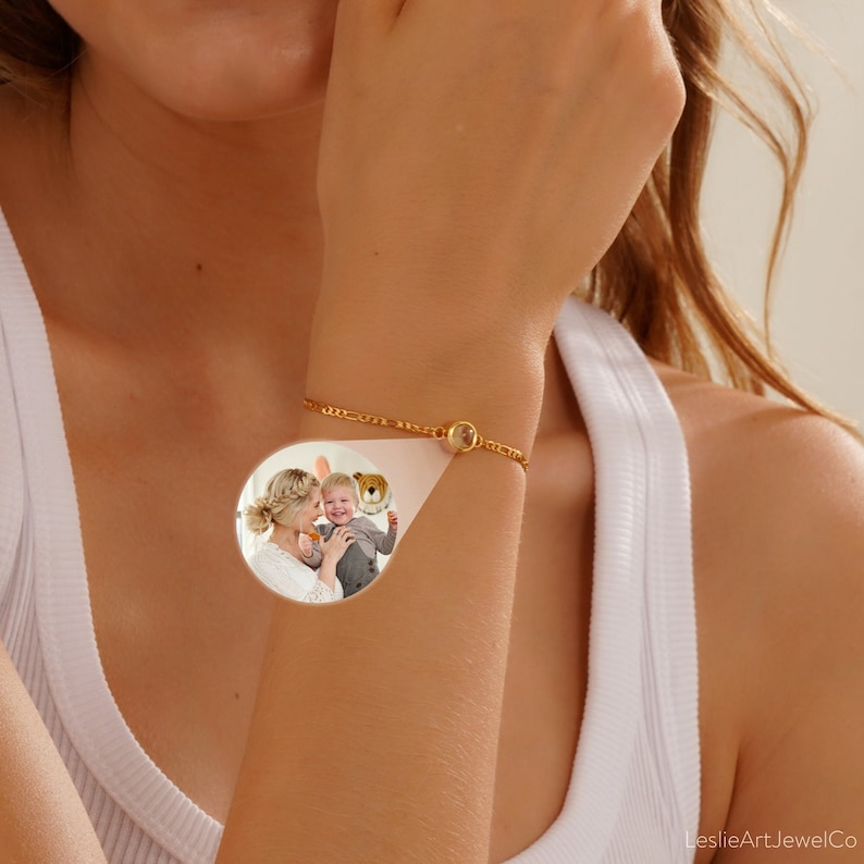 May include: A gold chain bracelet with a round clear glass charm featuring a photo of a woman and a child. The bracelet is on a person's wrist.