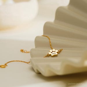 Pode incluir: Uma pulseira de corrente em tom dourado com um pingente central em forma de pata gravado com o nome Molly. A delicada corrente de metal conecta-se a ambos os lados do pingente, que exibe um acabamento polido e uma inscri&ccedil;&atilde;o clara e leg&iacute;vel.