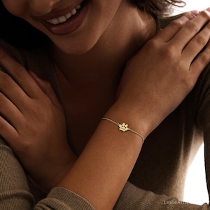 Pode incluir: Uma pulseira de corrente em tom dourado com um pingente central em forma de pegada de pata. O pingente est&aacute; gravado com o nome Molly em letra cursiva. A delicada corrente de metal prende-se ao redor do pulso com um fecho simples.