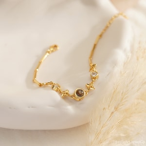 May include: A gold bracelet with a delicate chain and small, clear gemstones. The bracelet features a larger, round, brown gemstone in the center.
