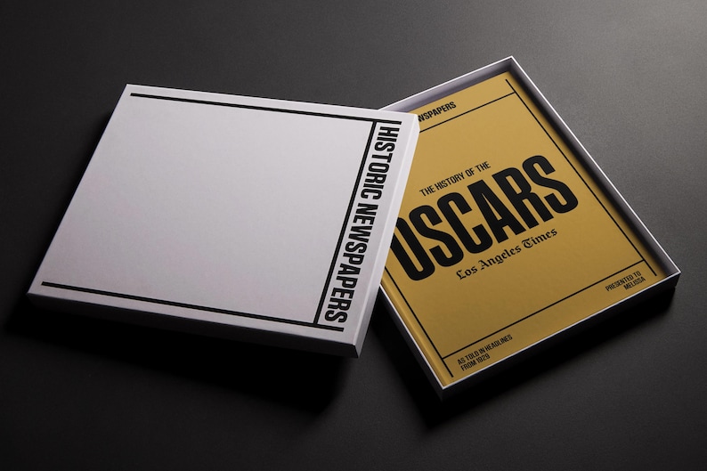 Puede incluir: Un libro cerrado con una cubierta blanca y texto negro que dice "Historic Newspapers: The History of the Oscars: Los Angeles Times". El libro est&aacute; abierto para revelar una cubierta amarilla con texto negro que dice "The History of the Oscars: Los Angeles Times".