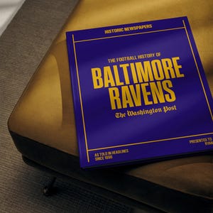 May include: A blue book with gold lettering titled "The Football History of Baltimore Ravens: The Washington Post, As Told in Headlines Since 1996".