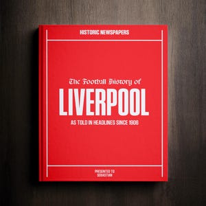 May include: A red hardcover book with the title "The Football History of LIVERPOOL" in white text. The subtitle is "As told in headlines since 1906". The book is presented to Sebastian.