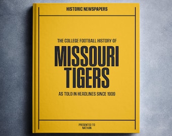 Könnte beinhalten: Ein Hardcover-Buch mit gelbem Einband und schwarzem Text. Der Titel lautet "The College Football History of Missouri Tigers as Told in Headlines Since 1909". Das Buch ist mit "Historic Newspapers" und "Presented to Nathan" beschriftet.