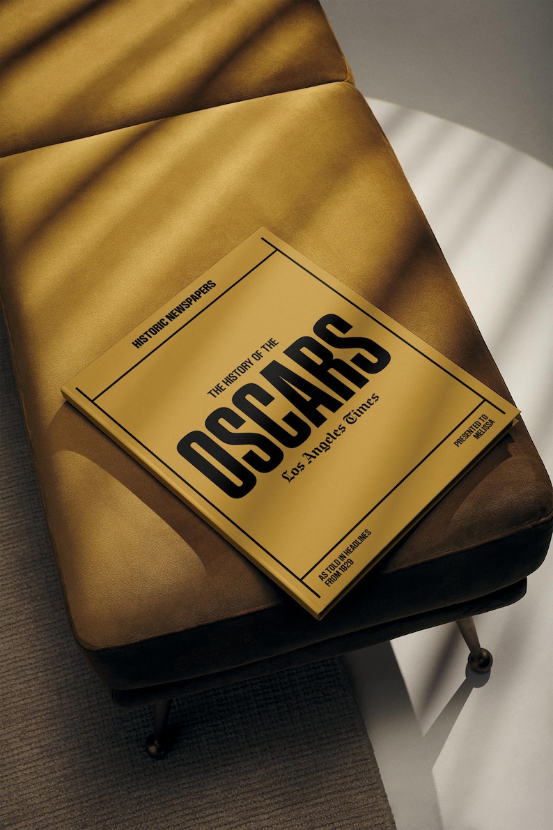Puede incluir: Un libro amarillo con el t&iacute;tulo "The History of the Oscars" en letras negras. El libro es del Los Angeles Times y presenta titulares de 1929.