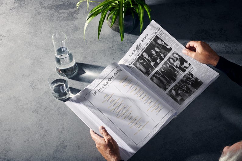 Puede incluir: Una persona leyendo un peri&oacute;dico titulado "The 16th Academy Awards" con una lista de ganadores. El peri&oacute;dico est&aacute; abierto en una p&aacute;gina con fotos de los ganadores del "Los Angeles Times" fechado el 29 de marzo de 1944.