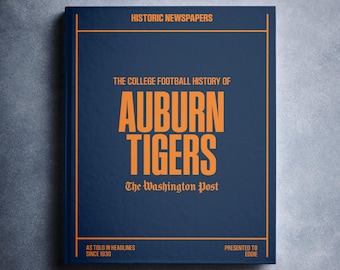 May include: A hardcover book titled "The College Football History of Auburn Tigers" from The Washington Post. The cover is navy blue with orange text and a thin orange border. The book is presented to Eddie and has headlines since 1930.