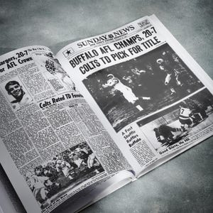 May include: A black and white newspaper with the headline "Buffalo AFL Champs, 20-7 Colts TD Pick for Title". The newspaper is open to a page with a photo of a football game. The photo shows a player in a white uniform catching a football.