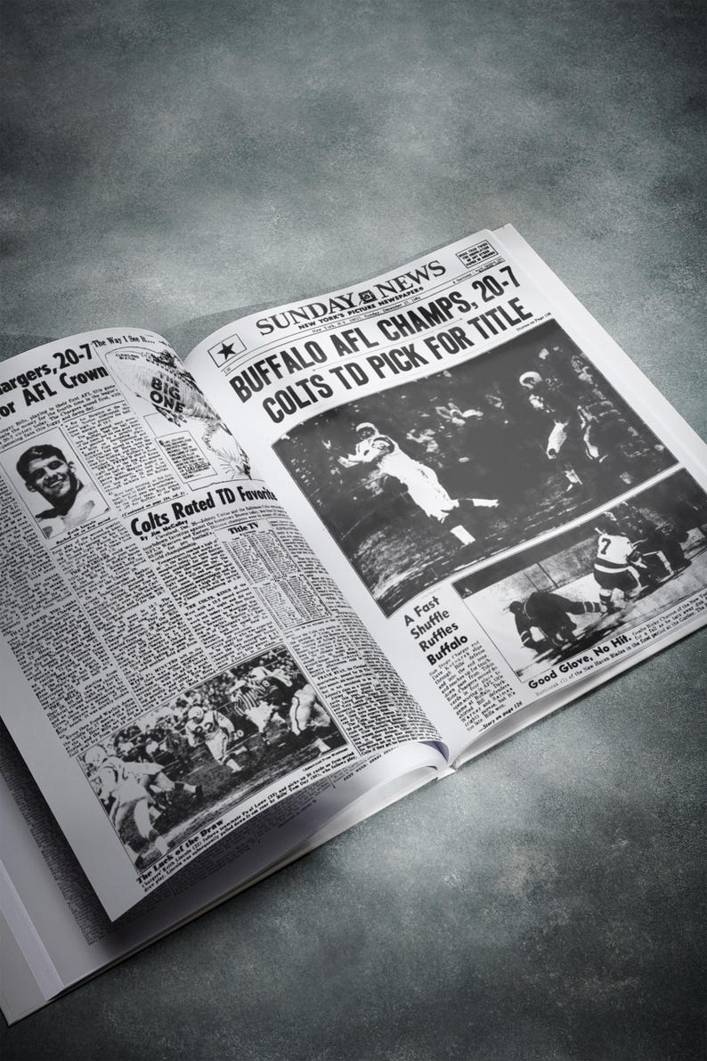 May include: A black and white newspaper with the headline "Buffalo AFL Champs, 20-7 Colts TD Pick for Title". The newspaper is open to a page with a photo of a football game. The photo shows a player in a white uniform catching a football.