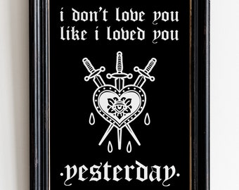 May include: Black framed art print with white text and a heart pierced by three swords. The text reads "i don't love you like i loved you yesterday."