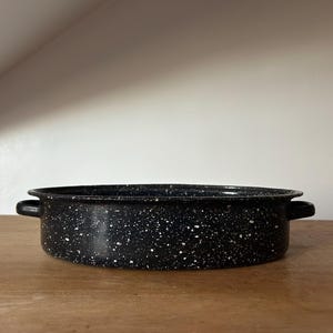 Puede incluir: Plato para hornear de esmalte negro con motas blancas y dos asas.