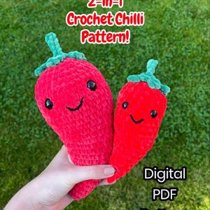 Puede incluir: Dos chiles rojos de ganchillo con caras sonrientes y tallos verdes se sostienen en una mano. La imagen incluye el texto "2-en-1 Crochet Chilli Pattern!" y "Digital PDF Pattern". Los chiles están sobre un fondo de hierba verde.