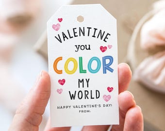Puede incluir: Etiqueta de regalo blanca con el texto "Valentine you color my world" en letras negras y arcoíris. La etiqueta está decorada con corazones rosas y rojos y el texto "Happy Valentine's Day! From:"