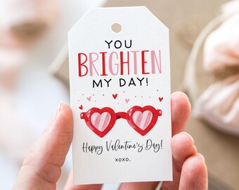 May include: White gift tag with red and pink text that reads "You brighten my day!" with a red heart-shaped sunglasses illustration and the text "Happy Valentine's Day! xoxo."