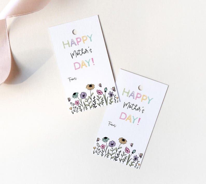 K&ouml;nnte beinhalten: Zwei wei&szlig;e Geschenkanh&auml;nger mit einem bunten Blumenrand und dem Text "Happy Mother's Day!" in Regenbogenfarben. Der Text "From:" ist unter dem Gru&szlig; gedruckt.