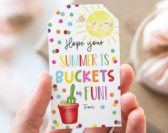 Puede incluir: Una etiqueta de regalo colorida con un sol y un cubo de arena. La etiqueta dice "¡Espero que tu verano esté lleno de diversión!" y tiene un espacio para escribir "De:"