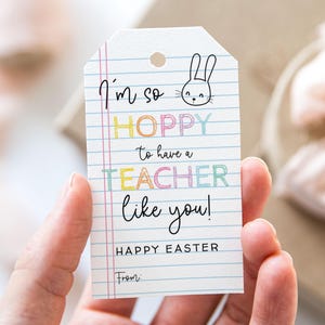 May include: A white gift tag with a bunny rabbit illustration and the text "I'm so hoppy to have a teacher like you! Happy Easter" in colorful letters. There is a blank space for a name at the bottom.