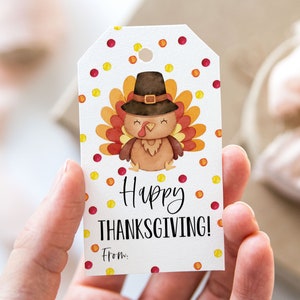 Könnte beinhalten: Ein weißer Geschenkanhänger mit einer bunten Truthahn-Illustration und dem Text "Happy Thanksgiving!" mit einem Platz für einen Namen unter "Von:". Der Hintergrund ist ein weißes Punkte-Muster mit roten und gelben Punkten.
