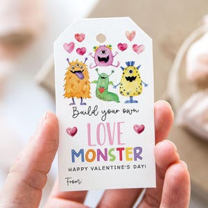 May include: A white gift tag featuring watercolor illustrations of colorful monsters and hearts. Text includes "Build your own LOVE MONSTER" and "HAPPY VALENTINE'S DAY!" with a space for "From:"