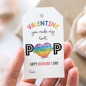 May include: A white Valentine's Day gift tag with a rainbow pop-it heart and the text "Valentine you make my heart POP Happy Valentine's Day! From:"
