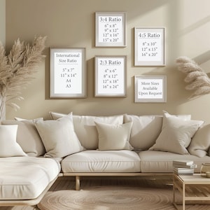 K&ouml;nnte beinhalten: Ein beiges L-f&ouml;rmiges Sofa mit drei Kissen steht in einem Raum mit einer hellbeigen Wand. An der Wand h&auml;ngen drei gerahmte Poster mit unterschiedlichen Gr&ouml;&szlig;enverh&auml;ltnissen und Ma&szlig;en. Die Poster listen verschiedene Gr&ouml;&szlig;en f&uuml;r verf&uuml;gbare Drucke auf. Die Poster sind in hellem Holz gerahmt. Ein kleiner Holztisch mit einem Stapel B&uuml;cher steht rechts neben dem Sofa. Ein gewebter Teppich liegt auf dem Boden vor dem Sofa.