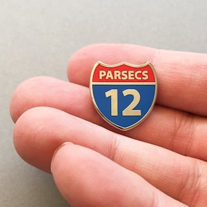 May include: A blue and red enamel pin shaped like a highway sign with the text "PARSECS 12" on it.
