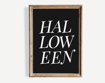 May include: A framed black and white Halloween sign. The word "HALLOWEEN" is written in a stylized font. The frame is a light brown color.
