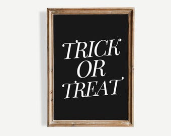 Könnte beinhalten: Ein gerahmtes schwarzes Schild mit den Worten "TRICK OR TREAT" in weißer, eleganter Schrift. Der Rahmen hat eine warme, hellbraune Farbe. Das Schild ist eine festliche Dekoration für Halloween.
